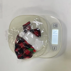 Close-up of red and black plaid Christmas bottle cover set being weighed on scale