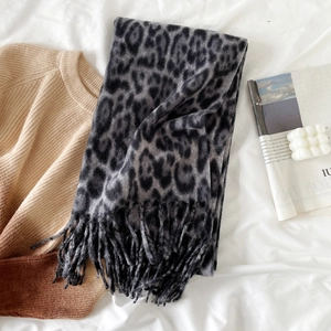 Detail of grey leopard print scarf with tassels styled on a beige knitted sweater