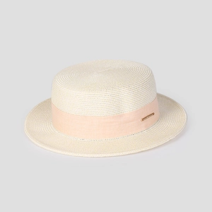 Détail de la texture d'un chapeau de paille beige avec ruban rose et plaque logo dorée