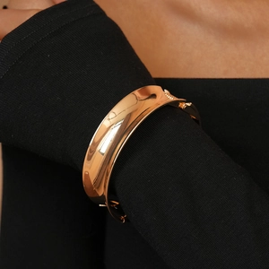 Detailed view of wide polished gold metal cuff bracelet with hinge closure for women