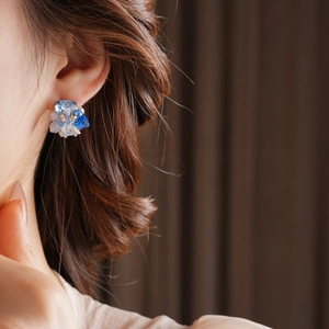 Detailed view of blue crystal flower cluster earrings worn on ear for elegant styling