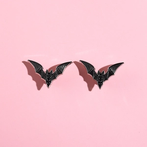 Gothic style black enamel bat brooch with silver metal edges on a pink background