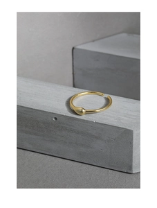 Makroaufnahme der minimalistischen Gold-Tränenring-Details auf grauem strukturiertem Stein