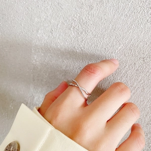 Close-up of a 925 sterling silver irregular crossover ring worn on a finger