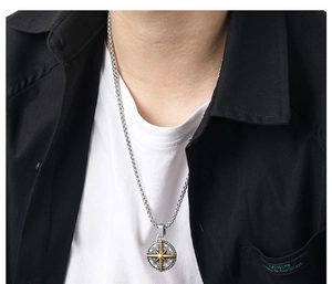 Close-up of a men's vintage compass pendant necklace in gold and silver on a model