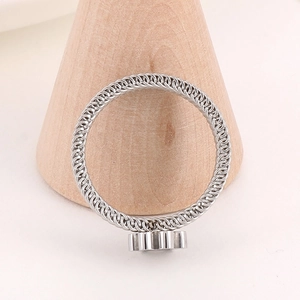 Detail of silver mesh band ring with industrial gear motif on a wooden display stand