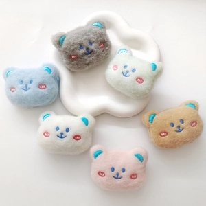 Flat lay of colorful plush bear head charms displayed on a cloud shaped ceramic tray