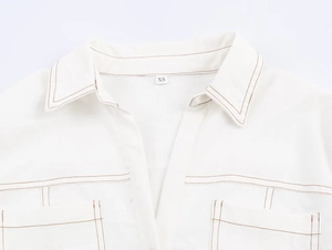 Détails de veste en jean blanc avec surpiqûres marron contrastées et étiquette de taille XS