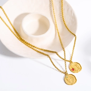 Close-up of gold Greek goddess coin necklaces with red and green gemstone accents