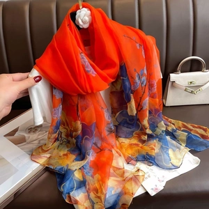Detail of thin floral gauze scarf in bright orange with artistic digital flower print
