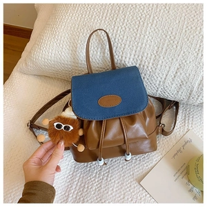 Detail of color-block mini backpack in blue and brown leather with plush pendant charm