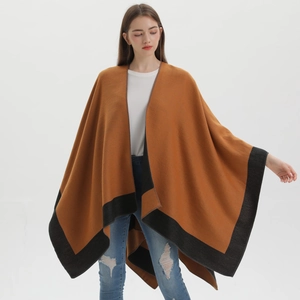 Stylishly draped brown knit shawl with black trim paired with blue distressed jeans