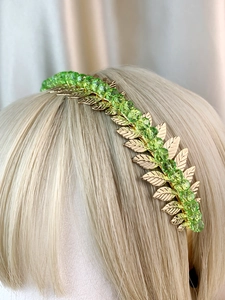 Detail of leaf-shaped golden headband with faceted green beads on a mannequin head
