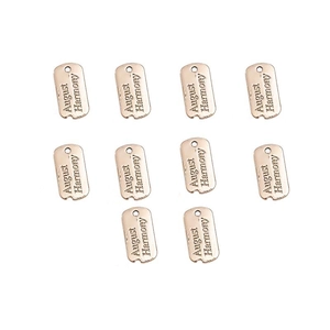 Macro shot of 10 rose gold alloy pendant charms with August Harmony engraved lettering