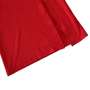 Detailed close-up of a red dress hem featuring a side slit and neat stitching craftsmanship