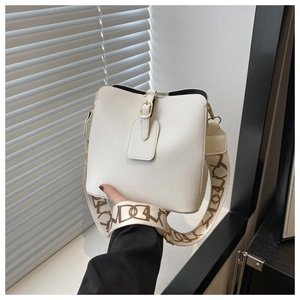 Detail of white bucket bag with lychee texture and patterned wide shoulder strap