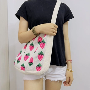 Detail of strawberry knit tote bag with pink and green patterns on beige texture