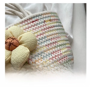 Close-up of woven cotton rope bag with colorful stitching and fabric flower detail