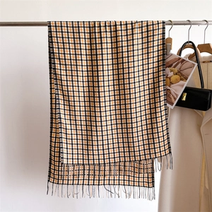 Close-up of soft yellow and black plaid scarf texture with elegant tassel details