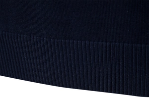 Détail macro de la maille côtelée bleu marine sur l'ourlet et les poignets du pull