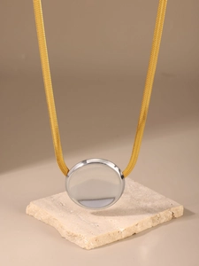 Close-up of dual-tone PVD 18K gold snake chain and silver disc pendant on stone base