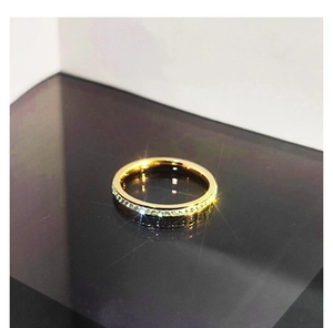 Close-up of gold titanium steel ring with micro-pave crystals on black reflective surface