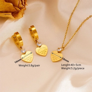 Golden titanium steel heart jewelry set with necklace and earrings on beige silk background