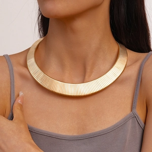 Macro detail of wide gold metal choker necklace with elegant vertical textured patterns