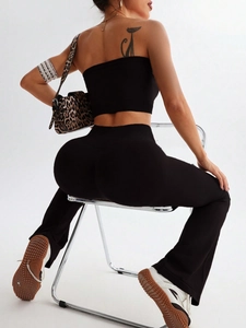 Detail of high-waist black seamless yoga set with flared pants and cropped tank top