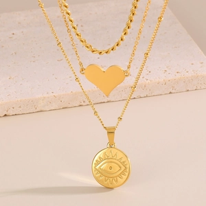 Collana dorata a strati con ciondoli a cuore e occhio su supporto in pietra beige