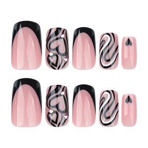 Short square press-on nails with nude pink base, black French tips and heart accents