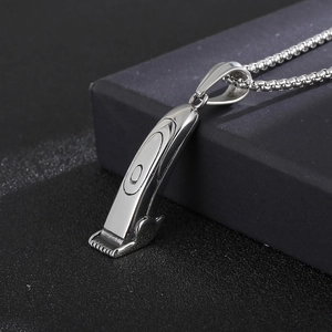 Vue macro d'un collier pendentif tondeuse à cheveux argenté sur boîte noire