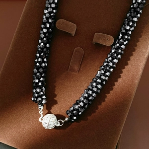 Close-up of black faceted beads and silver rhinestone magnetic clasp on a velvet stand