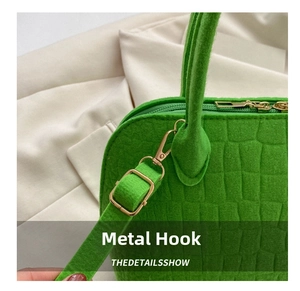 Detail of bright green crocodile texture felt handbag with premium gold metal hardware hooks