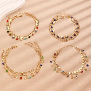 Detail of four gold-layered anklets with blue evil eye, stars, and coins charms
