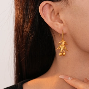 Vintage matte gold earrings with leaf and fruit design worn by a model in profile view