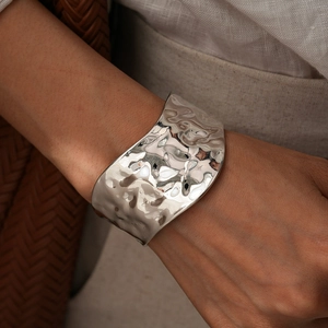 Macro shot of silver wide open cuff bracelet featuring irregular hammered wave texture