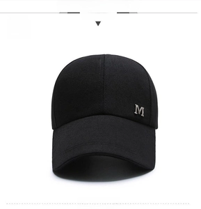Close-up of a black canvas baseball cap with a sophisticated metallic M logo on the side