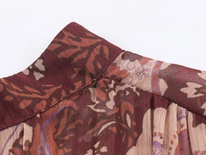Detail of red and brown paisley print chiffon dress showing neckline stitching and texture