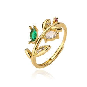 Macro detail of gold-plated leaf ring with red, green and white zircon stones