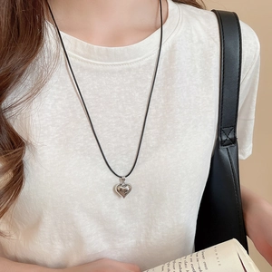 Close-up of heart-shaped silver pendant on a black cord necklace for daily style