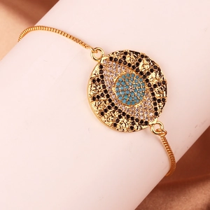 Detail of gold evil eye bracelet with colorful zircons on a soft beige fabric background