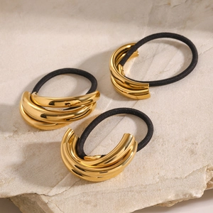 Three-piece gold metallic hair ties set with black elastic bands on stone background