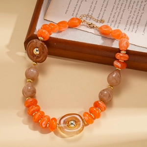 Close-up of orange acrylic irregular beads with marble pattern and golden metal spacers