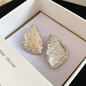 Detailed close-up of silver triangle earrings with modern hand-hammered texture