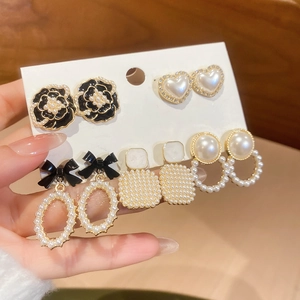 Macro detail of 5-piece earring set with black flowers, pearls, and gold finish