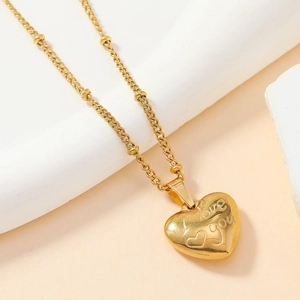 Detailed macro shot of gold heart pendant with I Love You engraving on beaded chain