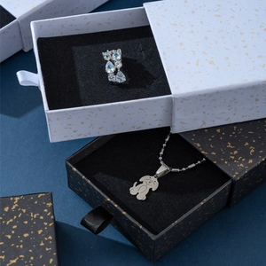 Dettaglio collana con cane e anello con gemma blu in scatole a cassetti puntinate d'oro