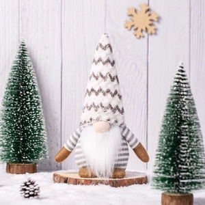 Nordic knitted Christmas gnome with white beard on snowy wooden background decorations