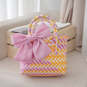 Close-up of pink and yellow woven basket bag featuring a large decorative satin bow
